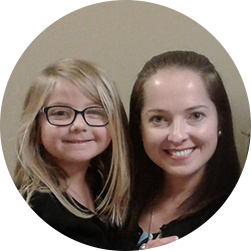 A young, happy mother and her smiling daughter embracing as they stand shoulder to shoulder together.