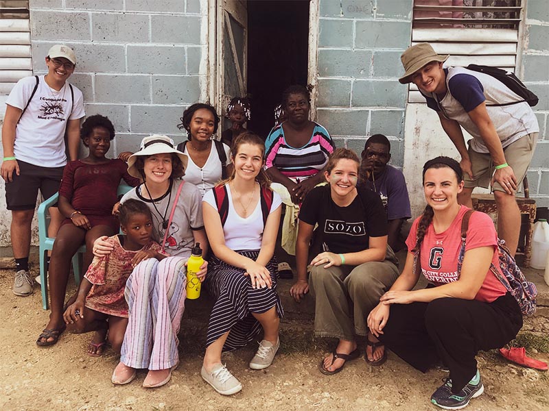 Young people on a mission trip sitting with residents and smiling