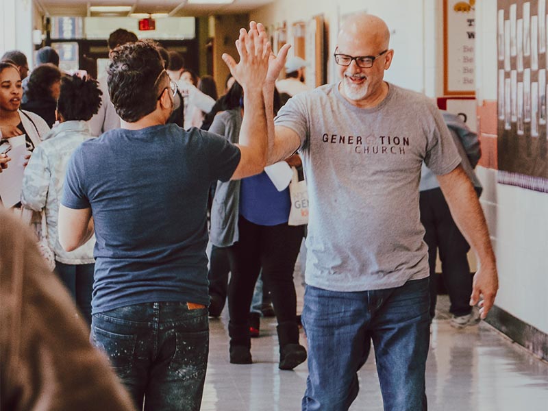 Two people high-fiving in a church lobby