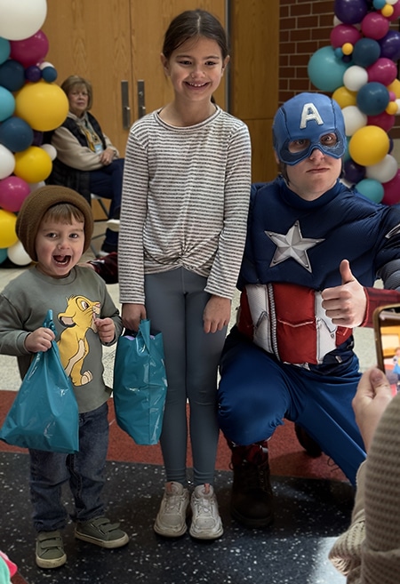 Two kids posing with person dressed up as Captain America at Eggstravaganza