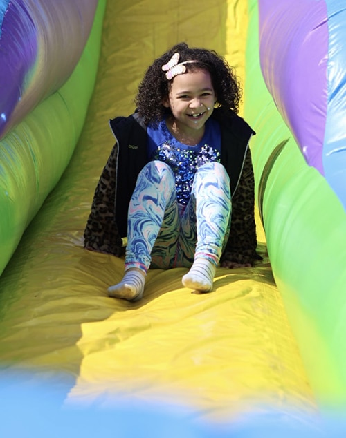 Young girl sliding down inflatable slide at Eggstravaganza